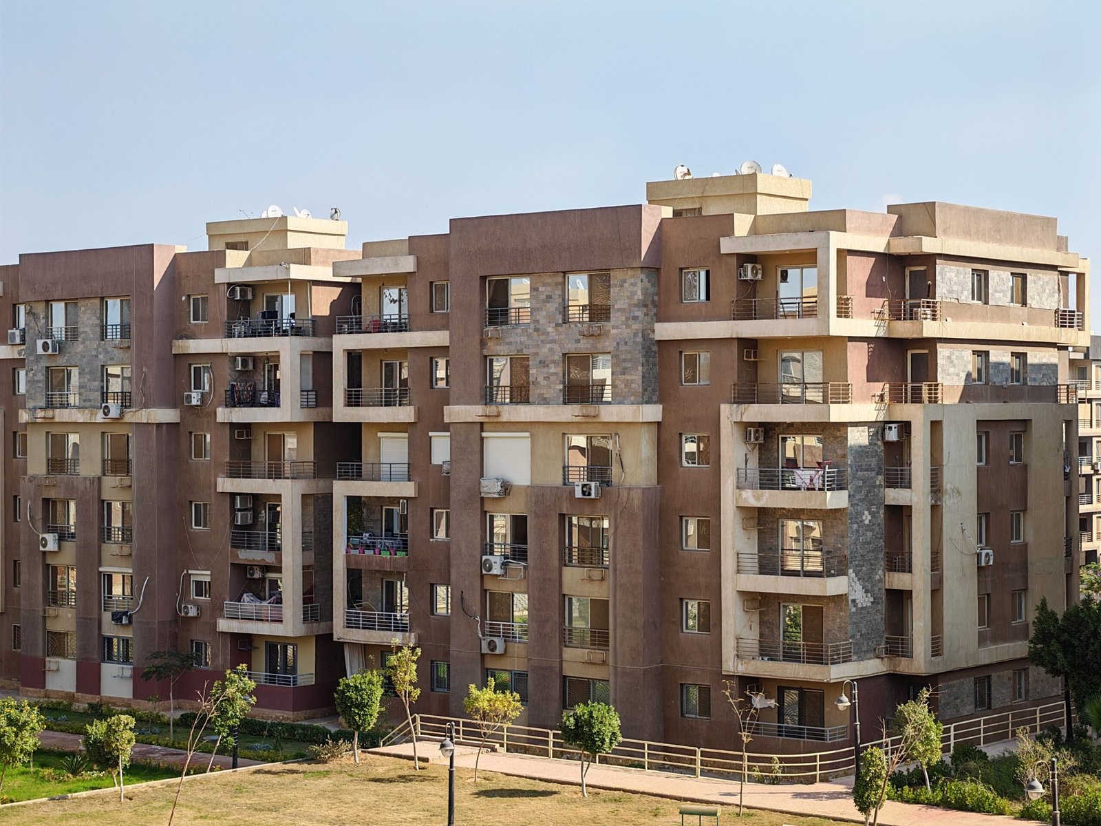 Home Contemporary multi-story apartment building with balconies in a sunny urban setting.